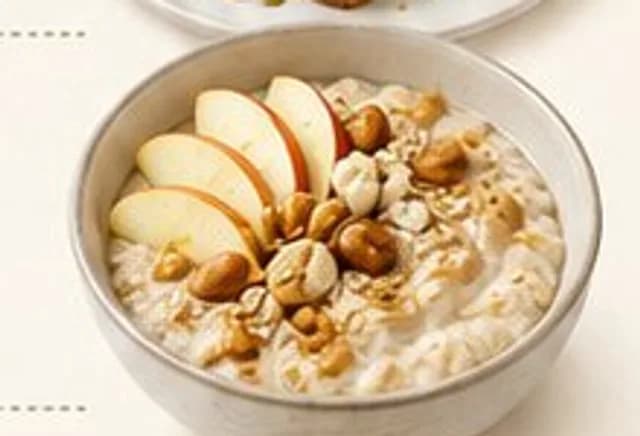 Miska ciepłej owsianki z plasterkami jabłka, orzechami i tahini